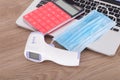 Upper mask, infrared thermometer and calculator on laptop keyboard Royalty Free Stock Photo