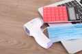 Upper mask, infrared thermometer and calculator on laptop keyboard Royalty Free Stock Photo