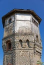 The upper part of an ancient watchtower made of stone blocks and wood paneling with windows against the blue sky on a bright sunny Royalty Free Stock Photo