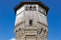 The upper part of an ancient watchtower made of stone blocks and wood paneling with windows against the blue sky on a bright sunny Royalty Free Stock Photo