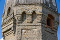 The upper part of an ancient watchtower made of stone blocks and wood paneling with windows against the blue sky on a bright sunny Royalty Free Stock Photo