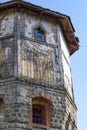 The upper part of an ancient watchtower made of stone blocks and wood paneling with windows against the blue sky Royalty Free Stock Photo