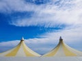 Upper part of a big colorful plastic tent. Blue sky and white clouds