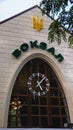 Upper part of the facade of the railway station with word Vokzal in ukrainian english: Station and modern clock