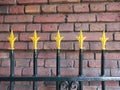 Upper part of a gate with yellow ornaments, fleur-de-lys