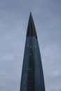 The upper part of the Lakhta Center skyscraper against a cloudy sky at twilight