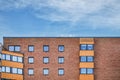 Upper part of modern apartments featuring an exterior made of orange firebricks and a pattern of windows and covered balconies Royalty Free Stock Photo