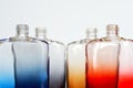 The upper part of multi-colored glass bottles for perfume or liquids on a light background. An example of color diffusion. Without Royalty Free Stock Photo