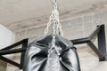 Upper part ob black punching boxing bag with chains closeup.