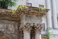 The upper part of the old building with stucco, arches and columns under large coniferous trees Royalty Free Stock Photo