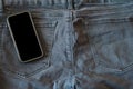 The upper part of old worn black jeans and a smartphone with a black screen Royalty Free Stock Photo