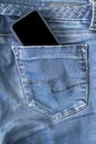 The upper part of old worn blue jeans and a smartphone with a black screen Royalty Free Stock Photo