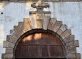 Upper part of the portal with wooden door, of an old building which is located near the south gate of Lucca where the tourist info Royalty Free Stock Photo