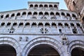 Upper part of the white facade, in the shadow of the cathedral of Lucca with a border of blue sky and part of the bell tower built Royalty Free Stock Photo