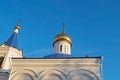 Upper part of white wall of the orthodox church with arched relief, bell tower with blue roofs and vaults and gilded domes crosse