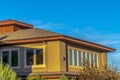 Upper storey of home with hip roof and brown wall against vibrant blue sky