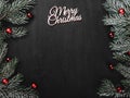 Upper, top, view from above, evergreen branches, tree globes and white Merry Christmas inscription on black background Royalty Free Stock Photo