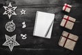 Upper, top, view from above of winter figurines, Christmas presents, notepad and pen on black background Royalty Free Stock Photo