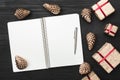 Upper, top view, of Christmas presents on a wooden black rustic background, note pad, pen with space for text. Royalty Free Stock Photo