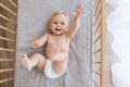 Upper view of little playful baby in diaper lying in bed reaching hand out to touch toy