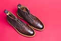 Upper View of Pair of Premium Dark Brown Grain Brogue Derby Boots Made of Calf Leather with Rubber Sole Placed On Pink