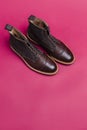 Upper View of Pair of Premium Dark Brown Grain Brogue Derby Boots Made of Calf Leather with Rubber Sole Placed On Pink Background