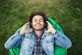 Upper view portrait of pleased relaxed african-american man with bristle lying on grass while listening music with Royalty Free Stock Photo