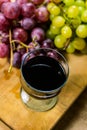 Upper view of a red and yellow muscat colored grape and a glass of wine on a wooden board - still life