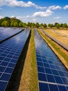 Upright image of solar modules of a PV plant with trees and clouds in the background