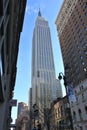 Upright shot of Empire State building seen from ground level, squeezed between two buildings