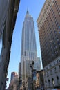 Upright shot of Empire State building seen from ground level, squeezed between two buildings