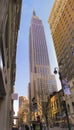 Upright shot of Empire State building seen from ground level, squeezed between two buildings