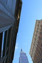 Upright shot of Empire State building seen from ground level, squeezed between two buildings