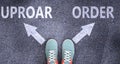 Uproar and order as different choices in life - pictured as words Uproar, order on a road to symbolize making decision and picking Royalty Free Stock Photo