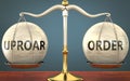 Uproar and order staying in balance - pictured as a metal scale with weights and labels uproar and order to symbolize balance and Royalty Free Stock Photo