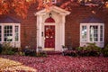 Upscale brick home with bay windows and columns in auturm with leaves covering the front yard and bushes and a no soliticting sign