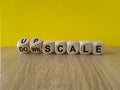 Upscale or downscale symbol. Concept words Upscale or Downscale on wooden cubes. Beautiful wooden table yellow background.