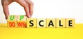 Upscale or downscale symbol. Concept words Upscale or Downscale on wooden cubes. Beautiful yellow table white background.