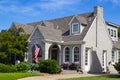 Upscale grey brick home with multiple gables and fireplace and landscaping and flowers and American Flags displayed Royalty Free Stock Photo