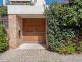 An upscale house entrance with a wooden door, and stonewalls partially covered by green foliage and an orange tree. Royalty Free Stock Photo