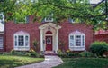 Upscale house with pillared porch and landscaping and bay windows with maple trees in front yard