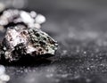 a shiny, metallic rock on a blurred surface, showcasing its unique texture and reflective qualities against a dark background. Royalty Free Stock Photo
