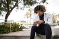 Upset african american middle aged male entrepreneur sitting on stairs outdoors and using cellphone, free space