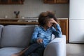 Unhappy African teenage girl crying seated alone on sofa Royalty Free Stock Photo