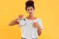 Upset african woman holding alarm clock and pointing on them Royalty Free Stock Photo