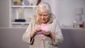 Upset aged female counting coins in hand, low pension income, retirement poverty Royalty Free Stock Photo