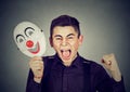 Upset angry screaming man holding clown mask expressing cheerfulness Royalty Free Stock Photo