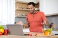 Upset angry young black man in red t-shirt gesturing with hands at computer, has problems with service Royalty Free Stock Photo