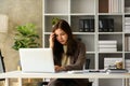 Upset asian businesswoman looking at laptop, frustrated about business failure in office