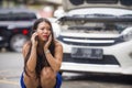 Upset Asian Japanese woman in stress stranded on street suffering car engine failure having mechanic problem calling on mobile Royalty Free Stock Photo